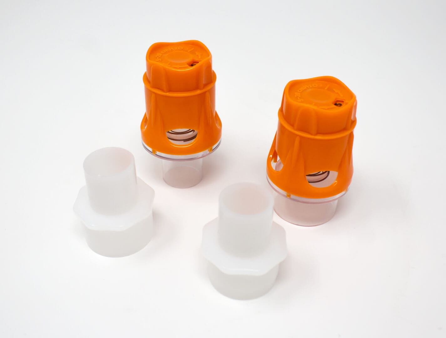 Zwei Koo stepPEEP-Ventile mit orangefarbenen Kappen und weißen Adaptern